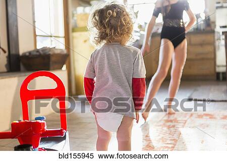 Stock Photography - Caucasian baby boy playing with older sister in kitchen. Fotosearch