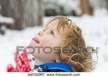 Stock Photo - Caucasian boy catching snowflakes on tongue. Fotosearch