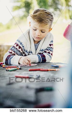 Stock Photo - Caucasian boy coloring outdoors. Fotosearch