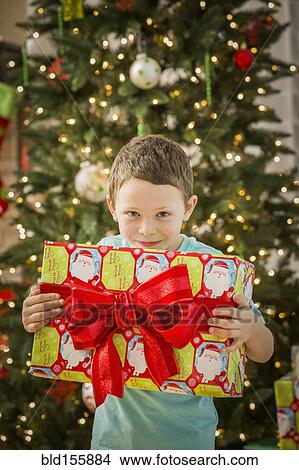 Picture - Caucasian boy holding Christmas gift. Fotosearch