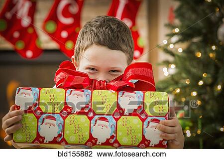 Stock Image - Caucasian boy holding Christmas gift. Fotosearch
