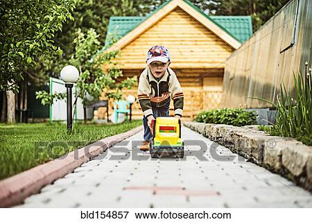 Caucasian boy playing with toy truck in backyard View Large Photo Image Stock Photo - Caucasian boy playing with toy truck in backyard. Fotosearch