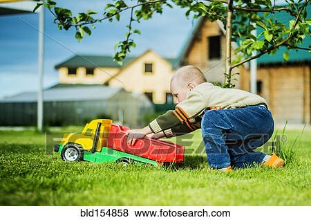 Caucasian boy playing with toy truck in backyard View Large Photo Image Stock Photo - Caucasian boy playing with toy truck in backyard. Fotosearch