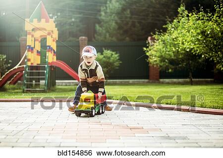 Caucasian boy playing with toy truck in playground View Large Photo Image Stock Photograph - Caucasian boy playing with toy truck in playground. Fotosearch