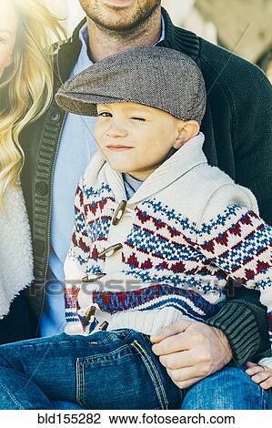 Caucasian boy winking on lap of father View Large Photo Image Stock Image - Caucasian boy winking on lap of father. Fotosearch