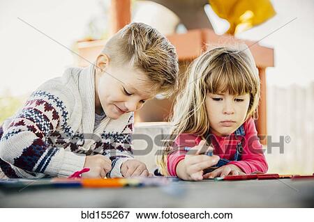 Stock Photo - Caucasian brother and sister coloring outdoors. Fotosearch