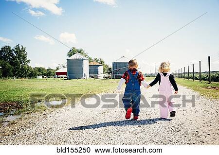 Stock Image - Caucasian brother and sister walking on farm. Fotosearch