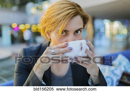 Stock Photography - Caucasian businesswoman drinking coffee at sidewalk cafe. Fotosearch
