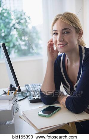 Stock Image - Caucasian businesswoman smiling at desk. Fotosearch