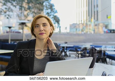Stock Image - Caucasian businesswoman working at sidewalk cafe. Fotosearch