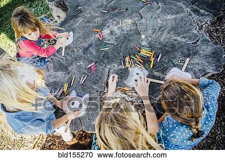 Stock Image - Caucasian children coloring on tree stump. Fotosearch