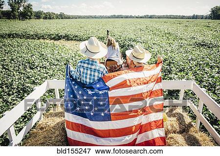 Stock Photo - Caucasian children holding American flag on hay ride. Fotosearch