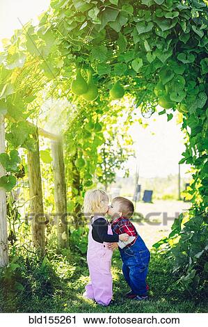 Stock Image - Caucasian children kissing under ivy leaves. Fotosearch