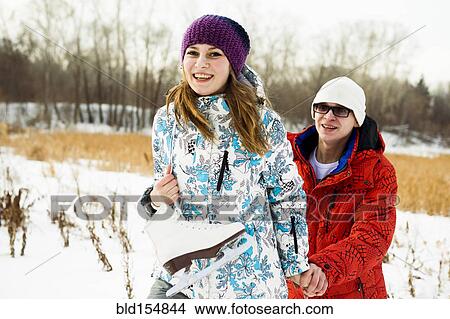 Picture - Caucasian couple carrying ice skates in snowy field. Fotosearch