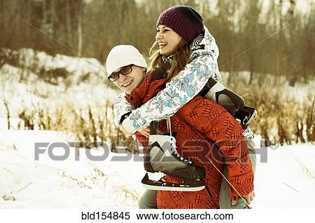 Stock Photography - Caucasian couple carrying ice skates in snowy field. Fotosearch
