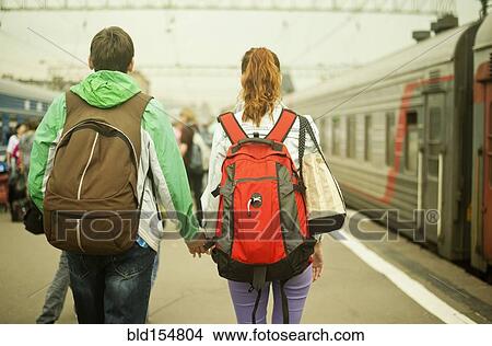 Picture - Caucasian couple holding hands on train station platform. Fotosearch