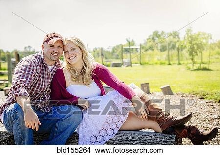 Picture - Caucasian couple kissing on log in park. Fotosearch