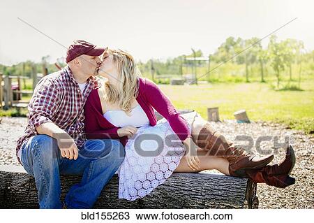 Caucasian couple kissing on wooden log in park View Large Photo Image Stock Image - Caucasian couple kissing on wooden log in park. Fotosearch