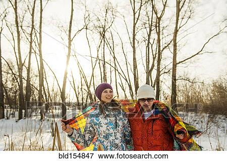 Stock Photo - Caucasian couple wrapped in blanket outdoors. Fotosearch