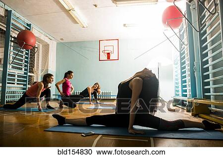 Stock Image - Caucasian dancers stretching in gym. Fotosearch