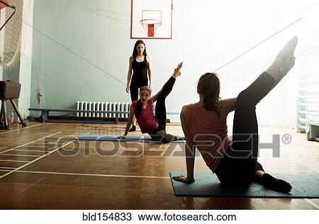 Stock Image - Caucasian dancers stretching in gym. Fotosearch