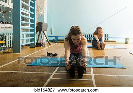 Stock Photo - Caucasian dancers stretching in gym. Fotosearch