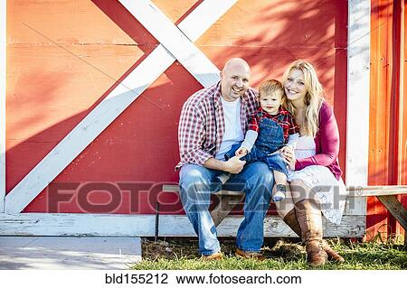 Stock Image - Caucasian family smiling outside barn. Fotosearch