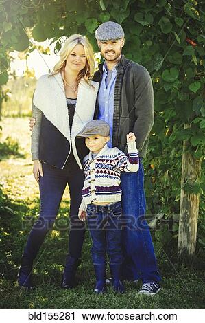 Stock Image - Caucasian family smiling under ivy leaves. Fotosearch