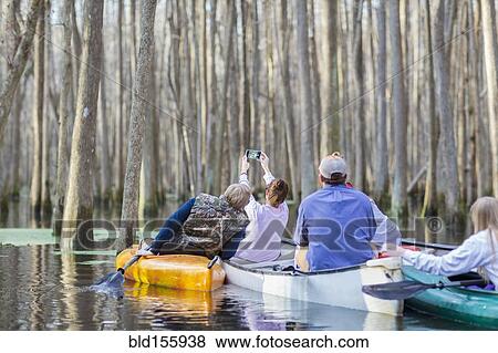 Caucasian family taking cell phone photographs in canoes on river View Large Photo Image Stock Photo - Caucasian family taking cell phone photographs in canoes on river. Fotosearch