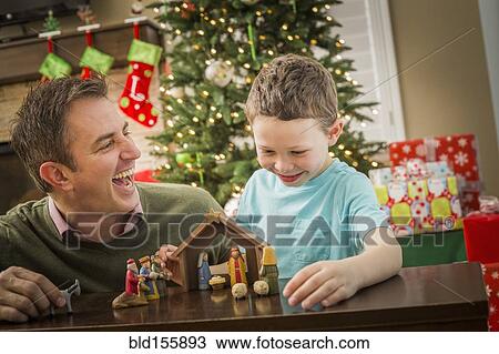 Stock Image - Caucasian father and son arranging nativity at Christmas. Fotosearch