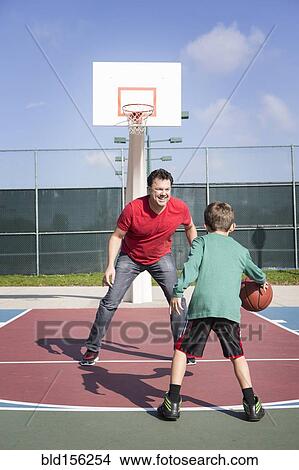 Picture - Caucasian father and son playing on basketball court. Fotosearch