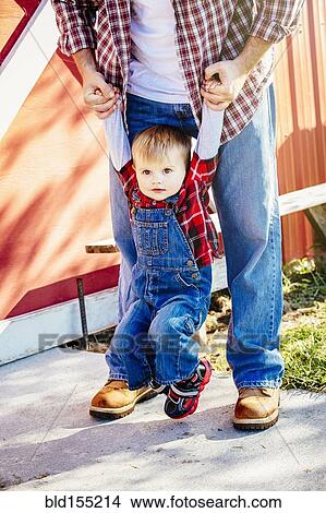 Picture - Caucasian father and son playing outside barn. Fotosearch