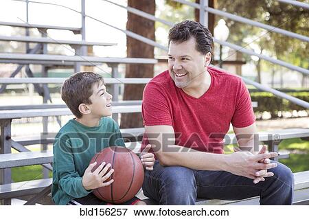 Stock Photo - Caucasian father and son talking on bleachers. Fotosearch