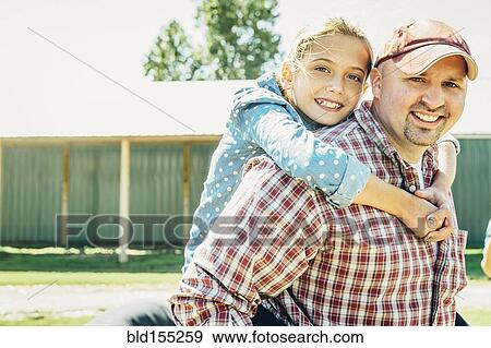 Stock Photo - Caucasian father carrying daughter piggyback on farm. Fotosearch