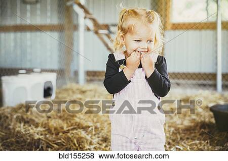 Stock Photo - Caucasian girl biting fingers in barn. Fotosearch