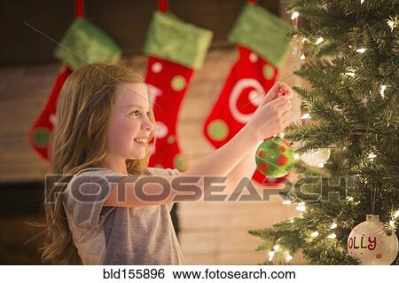 Stock Photograph - Caucasian girl decorating Christmas tree. Fotosearch