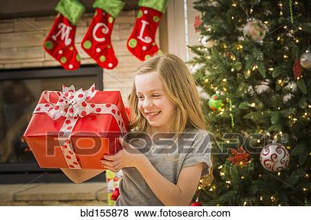 Caucasian girl examining Christmas gift View Large Photo Image Stock Photo - Caucasian girl examining Christmas gift. Fotosearch