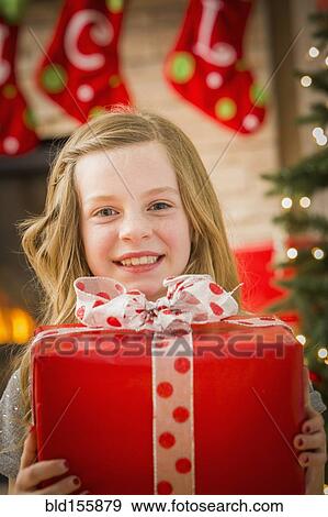 Stock Photo - Caucasian girl holding Christmas gift. Fotosearch