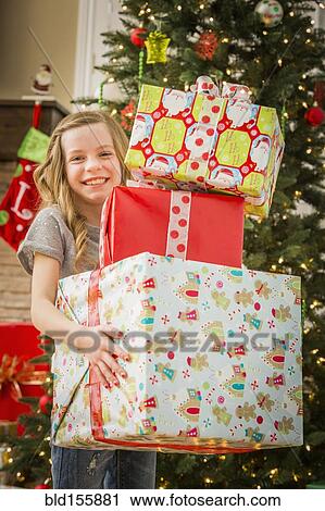 Stock Image - Caucasian girl holding pile of Christmas gifts. Fotosearch