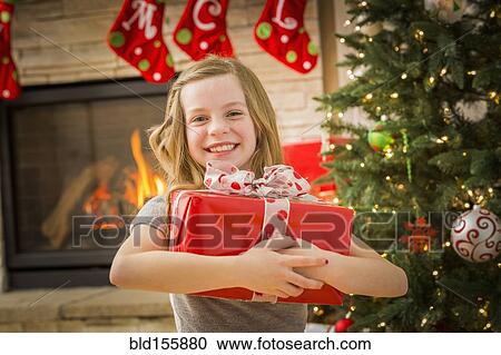 Stock Image - Caucasian girl hugging Christmas gift. Fotosearch
