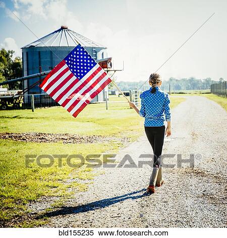 Stock Photography - Caucasian girl waving American flag on farm. Fotosearch