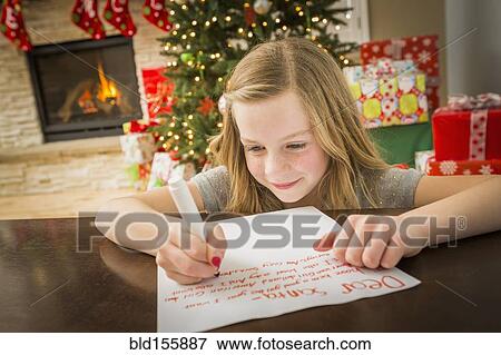 Stock Photo - Caucasian girl writing to Santa at Christmas. Fotosearch
