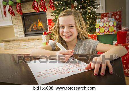Stock Photo - Caucasian girl writing to Santa at Christmas. Fotosearch