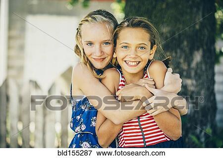 Stock Photo - Caucasian girls hugging outdoors. Fotosearch