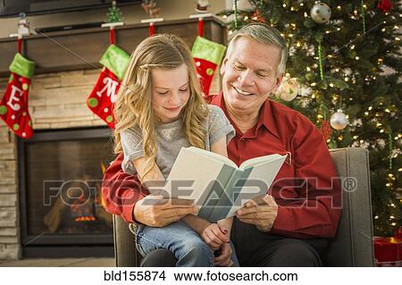 Picture - Caucasian grandfather reading to granddaughter at Christmas. Fotosearch