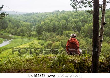 Stock Image - Caucasian man admiring scenic view from rural hilltop. Fotosearch