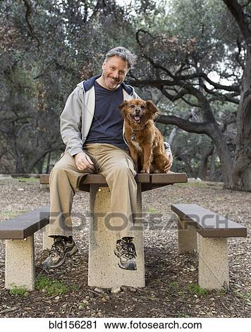 Caucasian man and dog sitting on picnic table in park View Large Photo Image Stock Image - Caucasian man and dog sitting on picnic table in park. Fotosearch