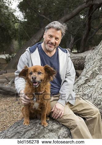 Caucasian man and dog sitting on tree in park View Large Photo Image Stock Photo - Caucasian man and dog sitting on tree in park. Fotosearch