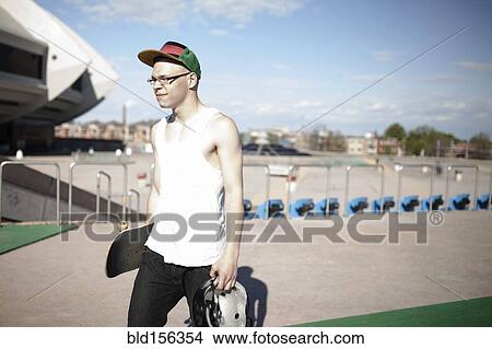 Caucasian man carrying skateboard near stadium View Large Photo Image Picture - Caucasian man carrying skateboard near stadium. Fotosearch