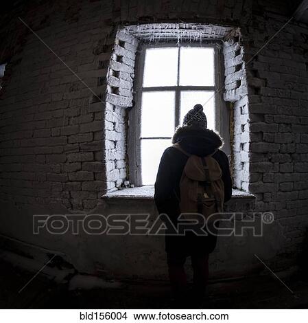 Picture - Caucasian man peeping through illuminated window at night. Fotosearch